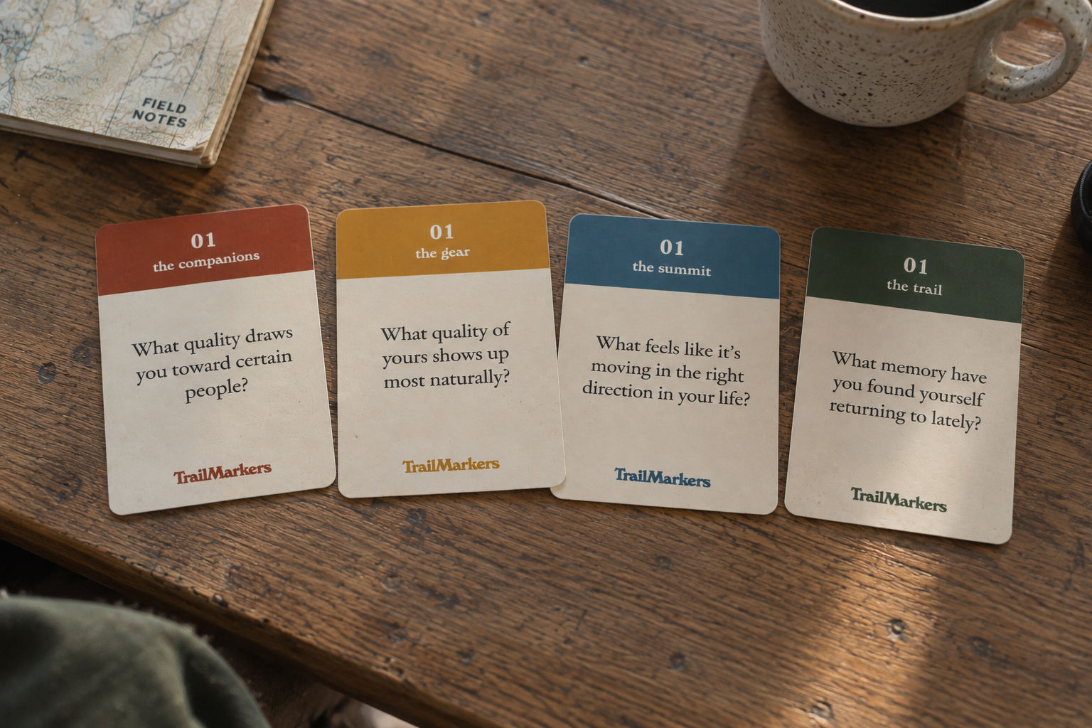 Four TrailMarkers card families arranged on a wooden table