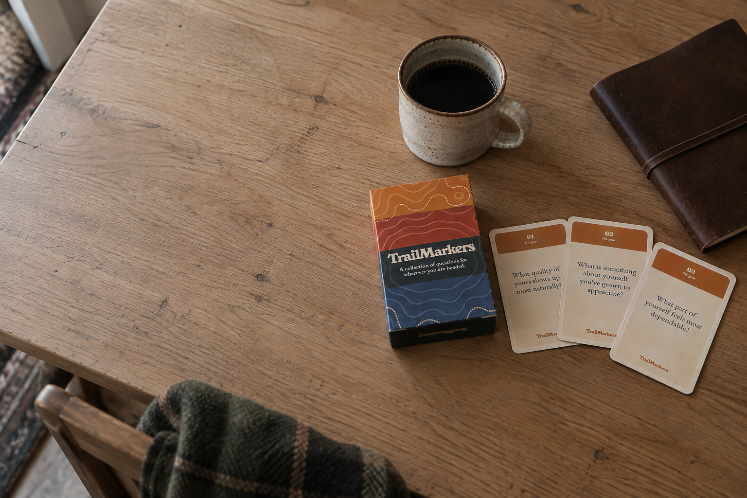 TrailMarkers cards, coffee, and a journal on a wooden table